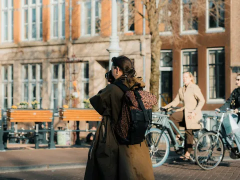 Mujer con cámara y mochila fotografiando una calle de Ámsterdam con ciclistas