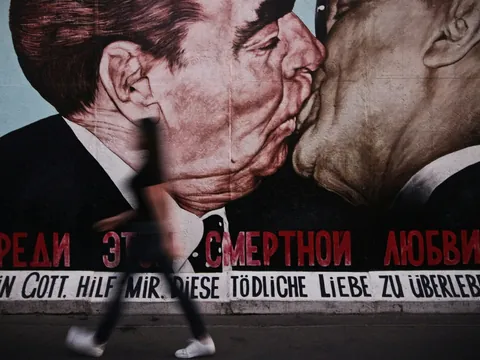 Mural del beso en el Muro de Berlín (East Side Gallery) con peatón pasando.