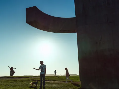 Personas junto al Elogio del Horizonte al atardecer en Gijón