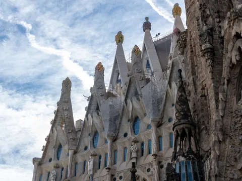 Detalle lateral de la Sagrada Familia con sus torres y esculturas bajo el cielo azul