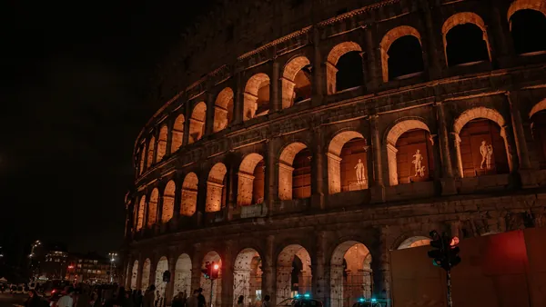 Coliseo de Roma iluminado de noche y esculturas visibles desde la calle