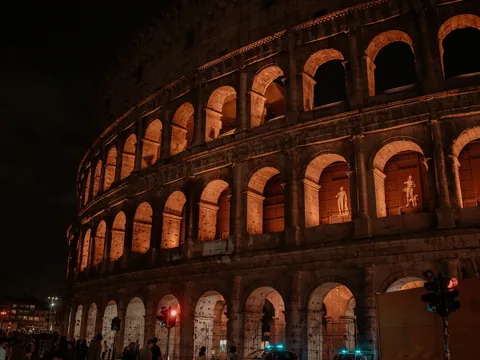 Coliseo de Roma iluminado de noche y esculturas visibles desde la calle