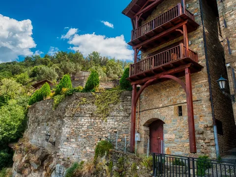 Edificio de piedra tradicional con balcones de madera en un acantilado de Aínsa.