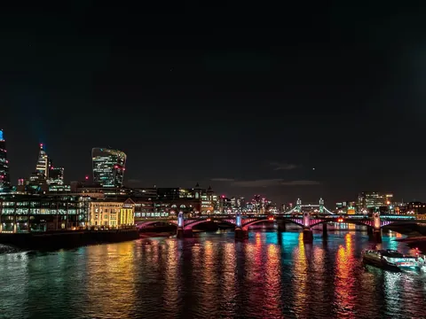 Puente de Southwark y rascacielos iluminados sobre el río Támesis de noche.
