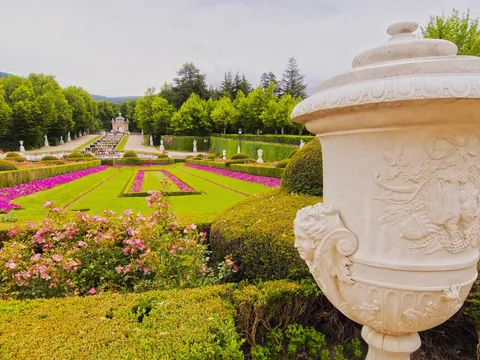 Urna de mármol en primer plano y parterres rosados en el Palacio de la Granja