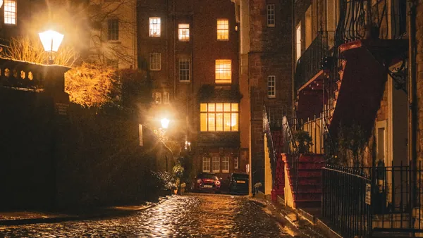 Calle adoquinada en el casco antiguo de Edimburgo, iluminada por farolas