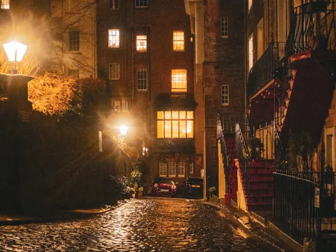 Calle adoquinada en el casco antiguo de Edimburgo, iluminada por farolas