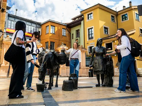 Turistas y guía de buendía junto a la estatua de "La Lechera" en la Plaza de Trascorrales, Oviedo.
