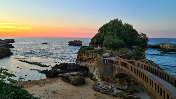 Puente que conecta con el islote de la Roca de la Virgen en Biarritz al atardecer, vista del mar y la costa vasca.