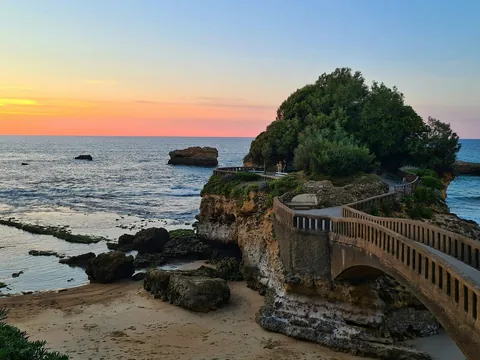 Puente que conecta con el islote de la Roca de la Virgen en Biarritz al atardecer, vista del mar y la costa vasca.