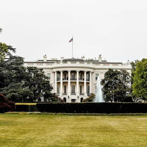 Vista frontal de la Casa Blanca en Washington D.C., con un jardín y una fuente en primer plano.