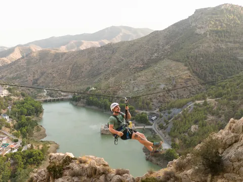 Hombre en tirolina sobre el embalse del Chorro, vía ferrata Caminito del Rey.