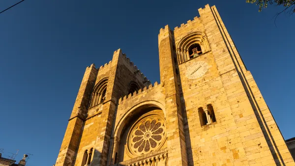 Fachada de la Catedral de Lisboa iluminada por el sol, con sus icónicas torres románicas.