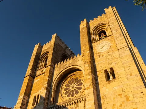 Fachada de la Catedral de Lisboa iluminada por el sol, con sus icónicas torres románicas.