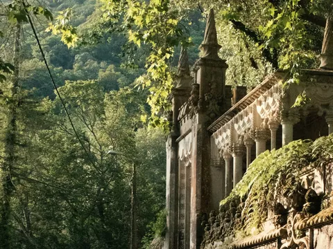Entrada lateral de la Quinta da Regaleira rodeada de vegetación frondosa.