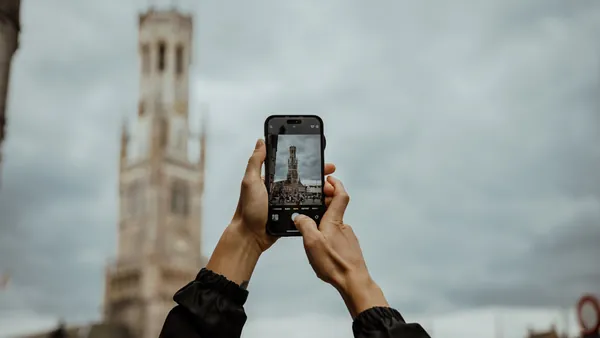 Joven hace una foto del campanario Belfort en Brujas, Bélgica