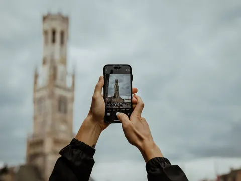 Joven hace una foto del campanario Belfort en Brujas, Bélgica