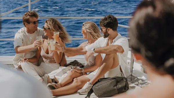 Un grupo de pasajeros disfruta del trayecto mientras el barco se desliza por el agua, con risas, sol y brisa marina.