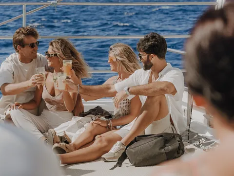 Un grupo de pasajeros disfruta del trayecto mientras el barco se desliza por el agua, con risas, sol y brisa marina.