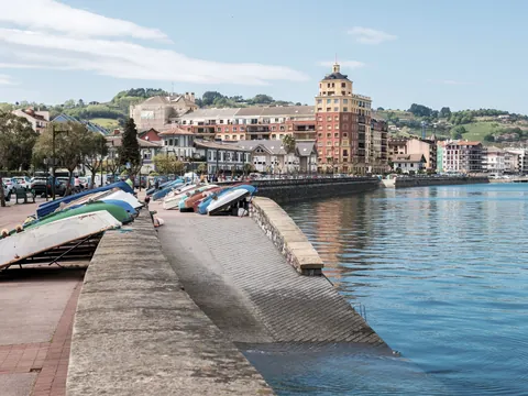 Barcas descansando junto al paseo marítimo de Hondarribia frente al agua y edificios.