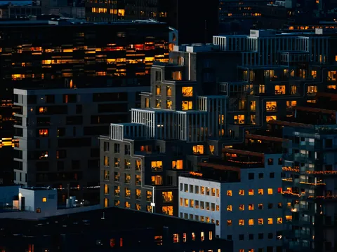 Edificios modernos iluminados al anochecer en el barrio de Bjørvika, Oslo, con arquitectura contemporánea.
