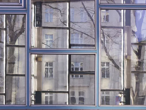 Reflejo distorsionado de un edificio y árboles en las ventanas del Tränenpalast en Berlín