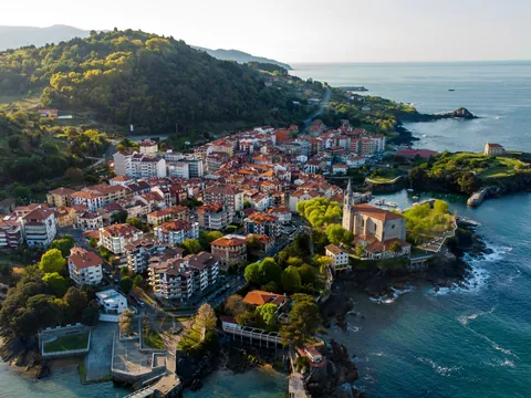 Vista aérea de Mundaka entre el mar Cantábrico y colinas verdes con su casco histórico.