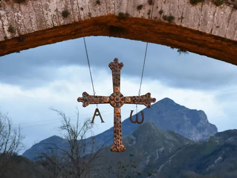 Cruz de la Victoria con montañas de Picos de Europa, colgada del Puente Romano en Cangas de Onís, Asturias.