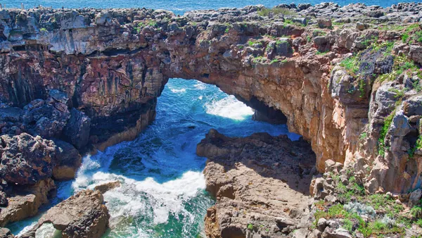 Acantilado de la Boca do Inferno en Cascais con olas rompiendo bajo el arco rocoso.