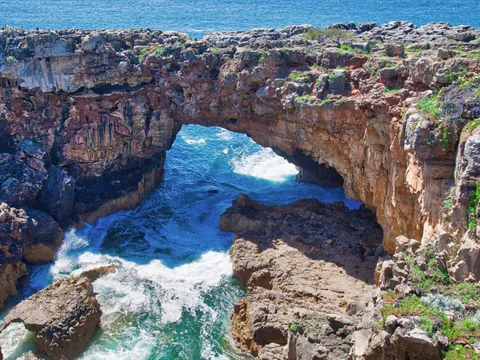 Acantilado de la Boca do Inferno en Cascais con olas rompiendo bajo el arco rocoso.