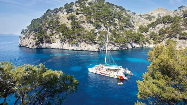 Catamarán navegando por las tranquilas aguas de la bahía de Alcudia, con vistas panorámicas al paisaje mediterráneo.