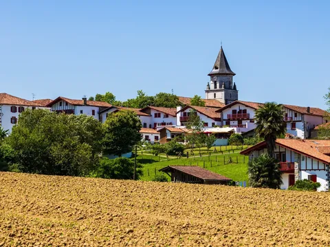 Pueblo de Bera con casas blancas y tejados rojos, rodeado de campos y la torre de su iglesia al fondo.
