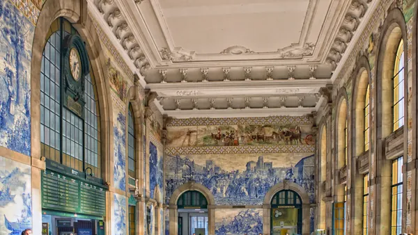 Interior de São Bento con murales de azulejos azules y gran reloj.