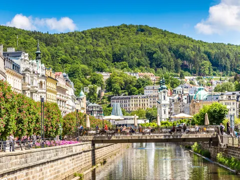 Río Teplá fluye entre edificios balneario y frondosas colinas en Karlovy Vary.