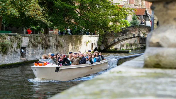 Excursionistas en paseo en barco por los canales de Brujas, Bélgica