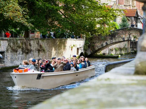 Excursionistas en paseo en barco por los canales de Brujas, Bélgica