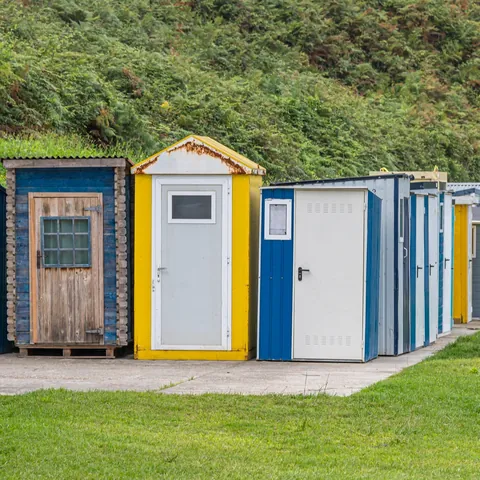 Casetas de colores para pesca alineadas en el puerto de Luarca, Asturias, junto al prado.