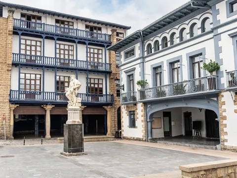 Plaza con estatua y edificios tradicionales con balcones en Guetaria.