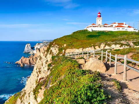 Acantilados y faro de Cabo da Roca con sendero junto al océano Atlántico.