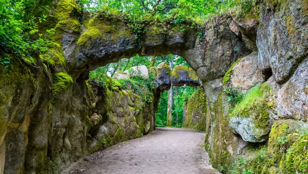Sendero con arcos de roca cubiertos de musgo en los jardines de Quinta da Regaleira, Sintra