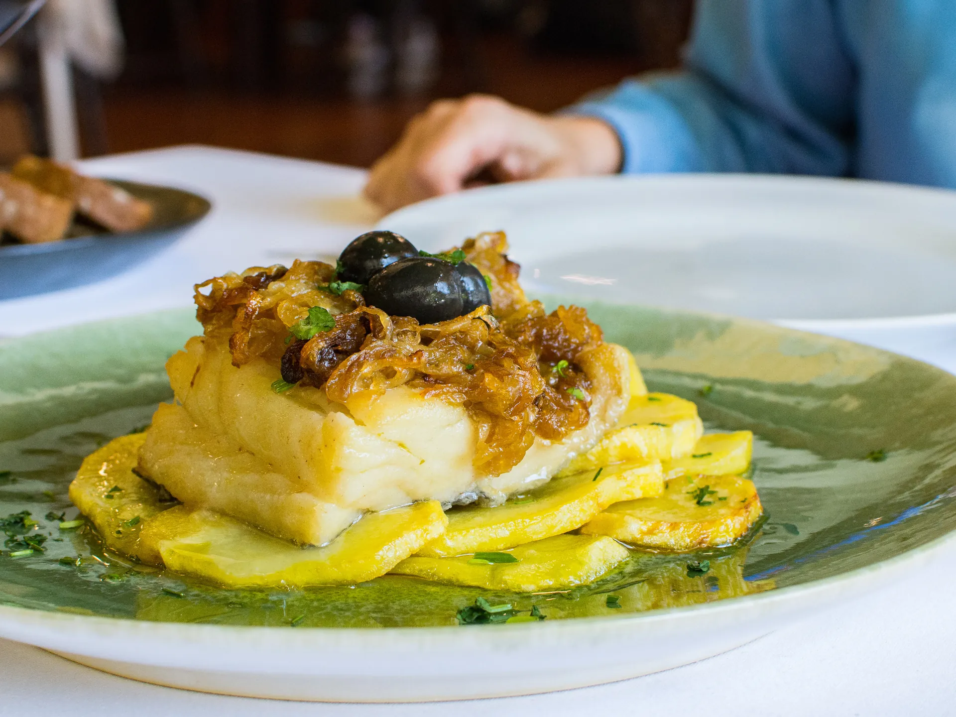 Mesa de un restaurante de Lisboa con un plato de Bacalao y un vaso de vino