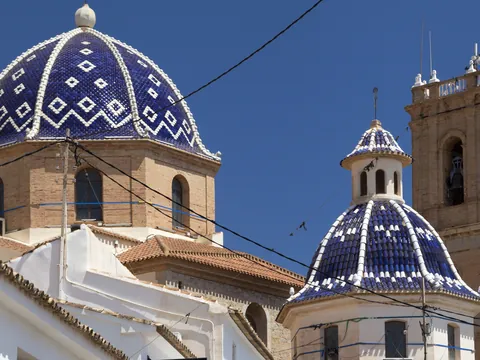 Cúpulas azules y campanario de la iglesia de Altea bajo un cielo despejado.