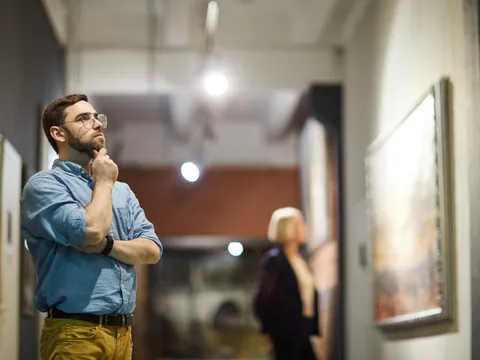 Visitante contemplando el arte que cuelga de las paredes.