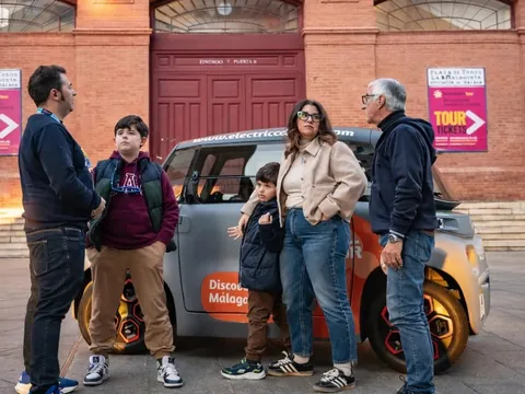Familia junto a un coche eléctrico frente a la Plaza de Toros de Málaga.