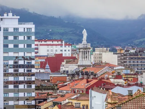 Panorámica de tejados en Gijón con el Monumento al Sagrado Corazón al fondo.