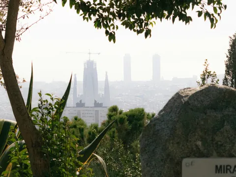 Vista lejana de la Sagrada Familia desde un mirador rodeado de vegetación