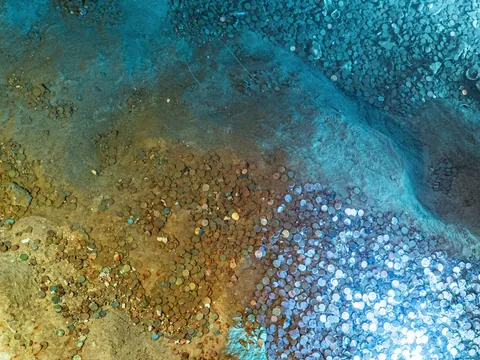 Monedas acumuladas en el fondo de la Cueva del Tesoro en Rincón de la Victoria.