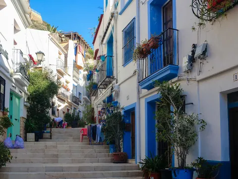 Calle escalonada con casas blancas y detalles azules en el barrio de Santa Cruz, Alicante