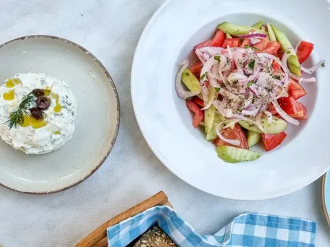 Ensalada griega fresca y salsa tzatziki servidas en platos blancos en Atenas