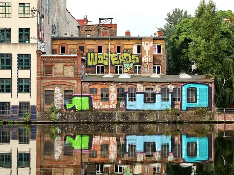 Edificios industriales con grafiti reflejados en el río Spree en Berlín.